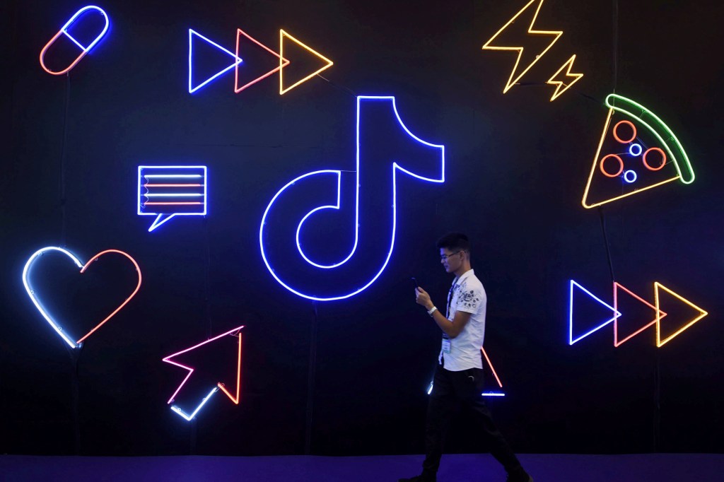 Man using a phone in front of a ticking logo and neon icons.